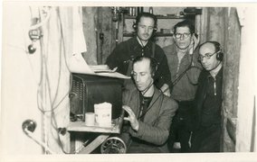 David Zivcon (seated) with Schmerl Skutelski, Michael Libauer, and Yosl Mandelštam (back, left to right) listening to the radio in the hiding place, Liepāja, 1944.